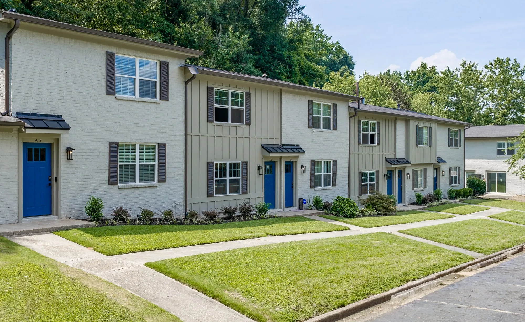 Row of white-brick townhomes with green lawn.