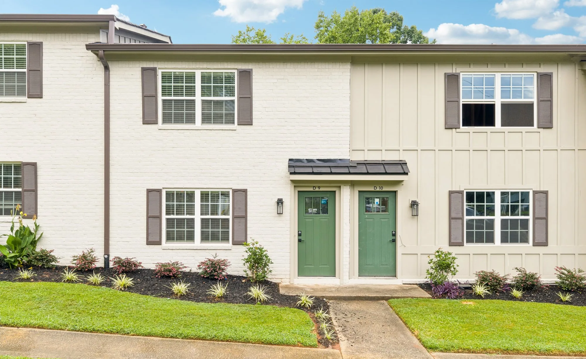 Townhome exterior with green door and fresh landscaping.